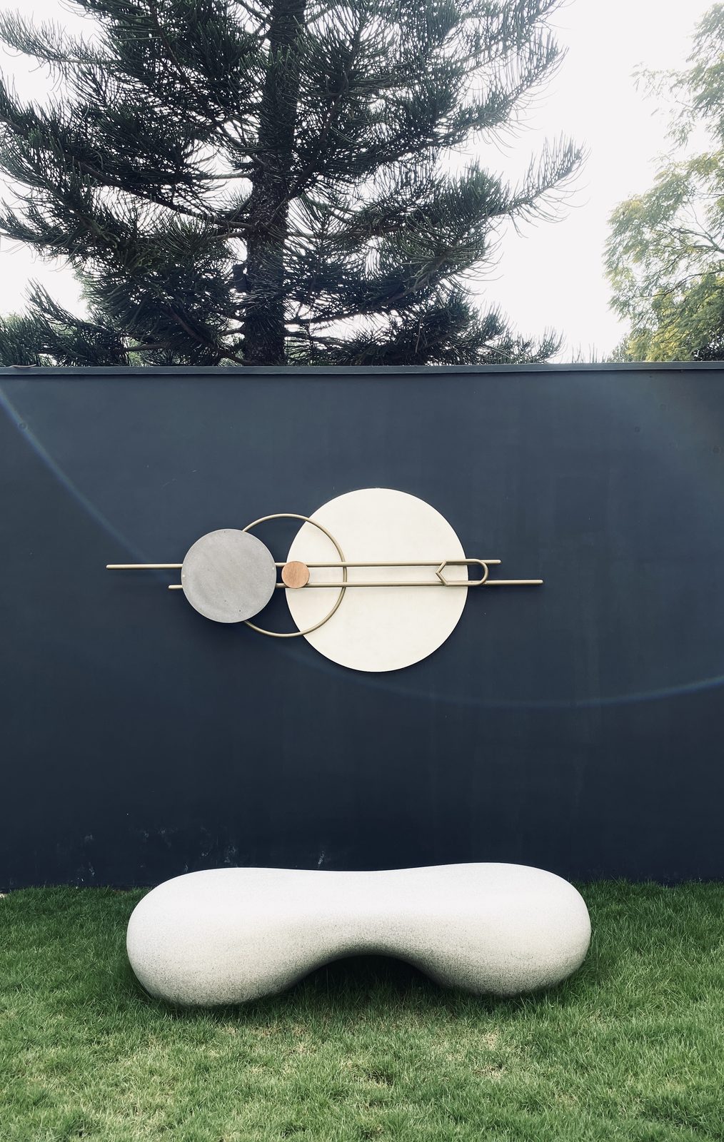 Bafna residence — circular brass-and-stone wall sculpture with cast bench
