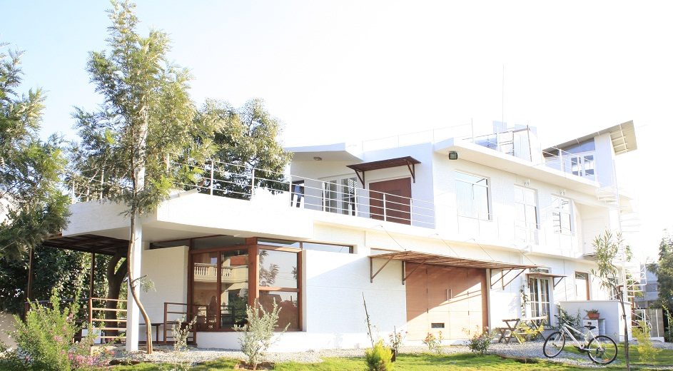 TA House — bright warm-modern family home seen across the garden