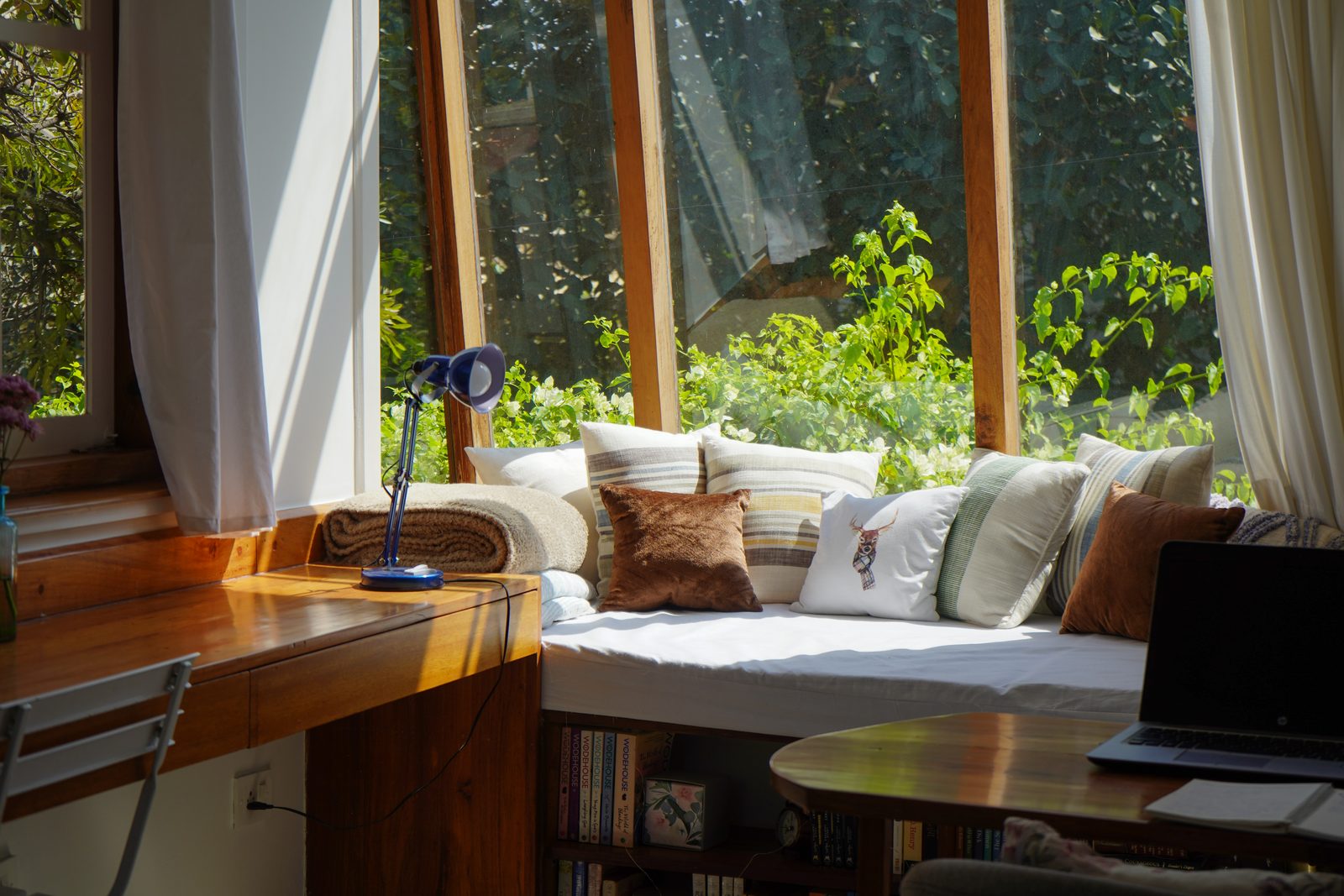 TA House — sunlit window-seat reading nook with angled glazing and garden views
