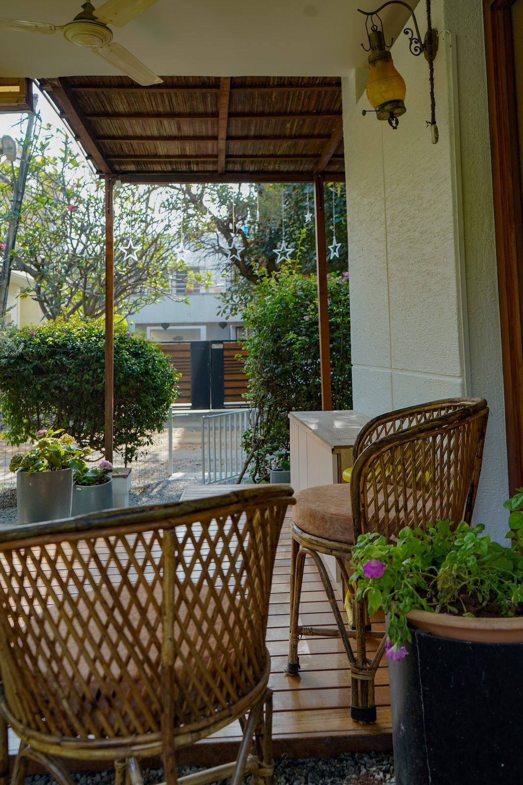 TA House — verandah sitting area with cane chairs and string lights