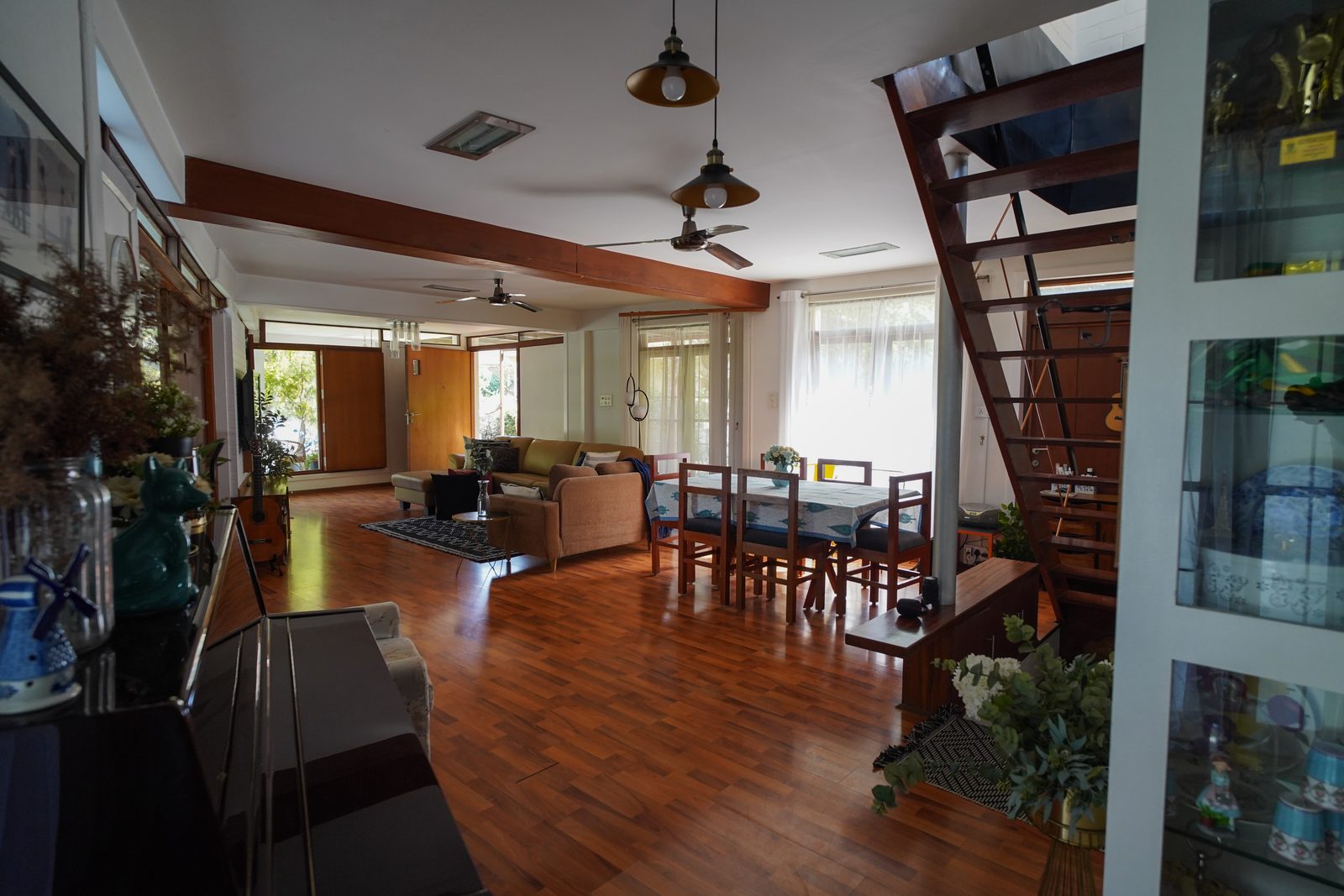 TA House — open-plan living and dining with exposed beams and floating staircase