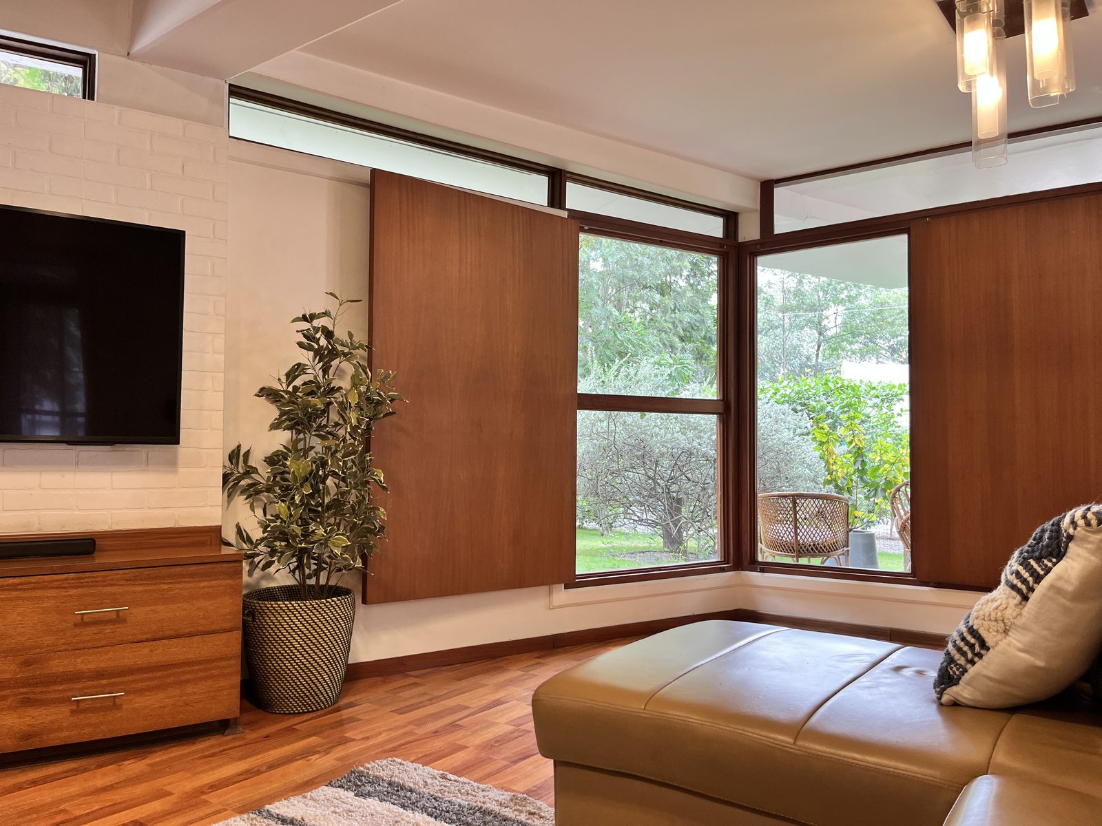 TA House — living corner with teak sliding panels and wraparound garden windows